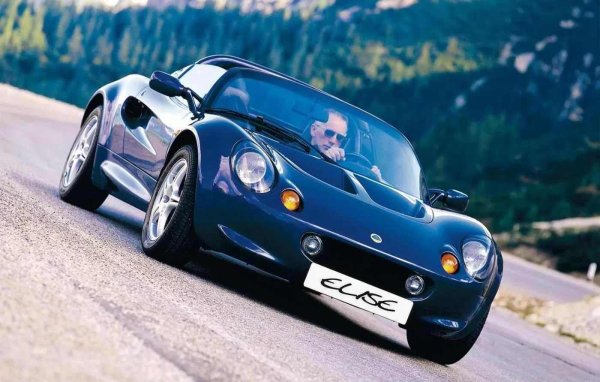 Колата е кръстена на Елиза Артиоли, внучка на Романо Артиоли, италианският предприемач, който по това време притежаваше Lotus и Bugatti. Елиза е само на няколко години, когато дядо ѝ решава, че името ѝ трябва да краси този нов лек спортен автомобил от малкото английско селце Хетел. Тя дори седи в прототипа по време на представянето, с широко отворени очи, облечена в малко зелено яке, и не подозира, че името ѝ ще бъде споменавано от автомобилните фенове в следващите три десетилетия.

Трудно е да си представим по-типичен за Lotus жест. Това не беше прекалено сложен проект за милиардери. Това беше минимализъм, въплъщаващ радост, чистота и връзка с колата - точно този подход, който би накарал легендарния Колин Чапман да се усмихне: "Първо опростете, след това добавете лекота". Elise не е просто лека, а духовно безтегловна.

Под каросерията от фибростъкло се крие алуминиева рама, толкова иновативна, че не изисква заваряване, а само съединени елементи, като тези в самолет. Двигателят е Rover K-series. Нищо екзотично, просто лек и пъргав - 118 к.с., 725 кг, и това беше достатъчно. Elise танцува, смее се и ни напомня, че по-малкото може да бъде повече, ако се направи както трябва.
