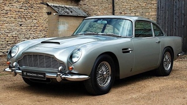 Джон Тейлър купува прекрасен Aston Martin DB5 от 1965 година в началото на 80-те. Басистът и основател на Duran Duran го поверява на специалистите от Chapman Spooner за цялостна реставрация. 
Като заклет фен на Джеймс Бонд, Джон Тейлър не може да не избере класически цветове, харесвани от шпионина на Нейно Величество. Това са легендарните "ilver Birch и Elephant Grey Connolly за интериора и тапицерията. 
Напълно реставриран през 1988 година, автомобилът е продаден от басиста през 1990-а. Оттогава колата е купувана и препродавана няколко пъти. 
Моделът е произведен от 1963 до 1965-а само в 1033 бройки. Дължи  голяма част от успеха си на класиката  "Goldfinger".  Джон Тейлър винаги е бил фен на Aston Martin DB5. В интервю признава, че е купил първия си само за $6700.