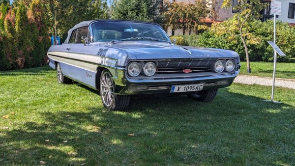 Година: 1961
В продължение на почти половин век, Ninety-Eight е флагманът на вече изчезналата американска марка Oldsmobile - пълноразмерен седан с 8-цилиндрови двигатели и богато оборудване. Този екземпляр е от седмото поколение, с 6.5-литров агрегат под внушителния капак. 
