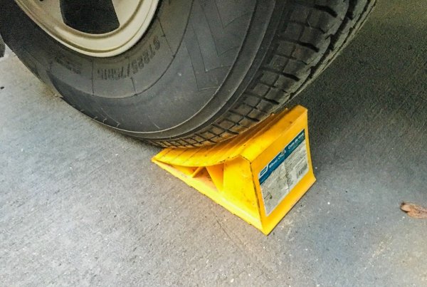 Това е малко спорен съвет, в интерес на истината. При по-старите автомобили действително дългият престой с вдигната ръчна може да залепи накладките за дисковете. Много експерти обаче твърдят, че при новите електронни ръчни спирачки няма такъв риск. При всички положения е полезно да имате чифт трупчета за подпиране на колелата. 
