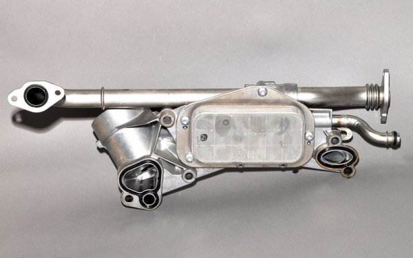 Той доста умно е разположен под тръбите на изпускателния колектор, като идеята е да изпълнява две функции: да подгрява маслото при студен старт и, обратното, да го охлажда при по-високи температури. Идеята е добра - само изпълнението куца. Множеството тръбички и каналчета за преминаване на маслото и антифриза са с доста посредствени уплътнения. Съответно много са възможни течове, особено след 80 000 км пробег. 
Когато маслото тече навън, не е толкова страшно - просто доливате. Но ако попадне в антифриза, става неприятно. Започва повишено износване на триещите се части в двигателя и дори появата на драскотини и пукнатини по повърхностите. 
