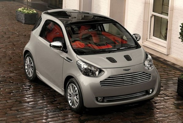 Както ви подсказват очите, тази кола не се е появила на чертожните дъски на дизайнерите на Aston Martin. Вместо това се е родила от перверзното бракосъчетание между малолитражката Toyota IQ и магазин за кожени палта. Смисълът на тази пародия бе да угоди на нелепите европейски правила за средни нива на вредните емисии. Въпреки че Cygnet струваше три пъти повече от оригиналната IQ, без да добавя нищо като задвижване, тогавашният шеф на Aston Улрих Бец прогнозираше 4000 продажби годишно за следващата петилетка. Вместо това едва 597 души се излъгаха да си купят тази нелепост и производството спря в края на втората година.