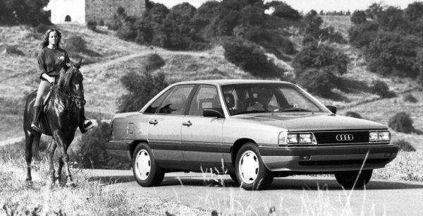 През 80-те години Audi прави големи усилия най-после да пробие на северноамериканския пазар. Основното оръжие е моделът Audi 5000 - всъщност вариант на европейското Audi 100. Но скоро след дебюта в САЩ започват обвинения, че автомобилът е склонен към внезапно ускорение, когато автоматичната трансмисия се превключи от положение Р. Компанията е принудена да обяви три сервизни акции, продажбите й спадат драстично, особено след като е изобличена със специално издание на нашумялото тв предаване "60 минути", и в крайна сметка задълго се оттегля от пазара в Америка. 
Трябва да минат още немалко години, преди успоредни разследвания на канадските транспортни власти и на щатския институт NHTSA да потвърдят това, което твърди компанията от самото начало - че повечето от злополуките са резултат на шофьорски грешки. Констатирани са механични причини само в няколко случая, в които автомобилите са оборудвани с круиз контрол на финландската Hella. 

