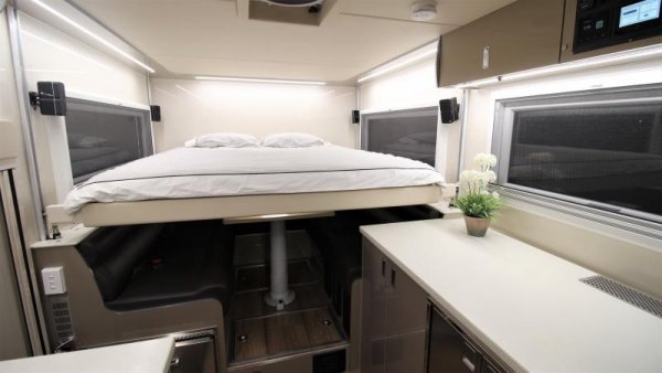 Тук хитрият трик за повече място е монтираното на хидравличен повдигач легло. През деня то е вдигнато до тавана, оставяйки отдолу удобно пространство с две диванчета и масичка. А когато ви се доспи, само натискате един бутон, и то се спуска надолу. По желание на клиента леглото може да е и неподвижно. 
