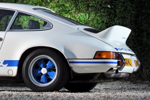 При висока скорост формата на Porsche 911 може да генерира подемна сила в задната част, което води до олекотяване на задницата. Поради това, за модела Carrera RS 2.7, германският производител разработва заден спойлер, интегриран в капака на двигателя, с цел подобряване на аеродинамичните характеристики и стабилността. Характерният му повдигнат ръб наподобява патешка опашка, откъдето идва и прозвището му &bdquo;ducktail&ldquo;. Това решение не само подобрява пътното поведение на автомобила, но и осезаемо променя дизайна на задната част, превръщайки се в един от най-емблематичните детайли в историята на модела.