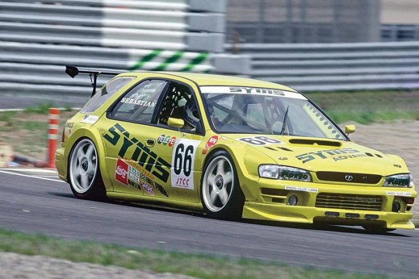 Въпреки че използваше всеобхватните правила Super Touring, Японският шампионат за туристически автомобили - JTCC се отличаваше доста от другите серии в средата на 90-те години благодарение на множеството местни отбори, които заявяваха уникални автомобили. Сред тях беше и тунинг компанията на Subaru &ndash; SYMS Racing, която реши да пусне първо поколение Impreza във вариант комби.

За съжаление, то не пожъна успех, като дори не успя да стигне до стартовата решетка за пет от 12-те състезания в дебютния си сезон през 1996. Отборът си взе година почивка за 1997 и се завърна през &rsquo;98-ма с подобрен автомобил, но нямаше никакъв шанс срещу конкуренцията от силно развити Toyota Corona и Chaser, участвайки само в три кръга, преди екипът да се откаже окончателно.
